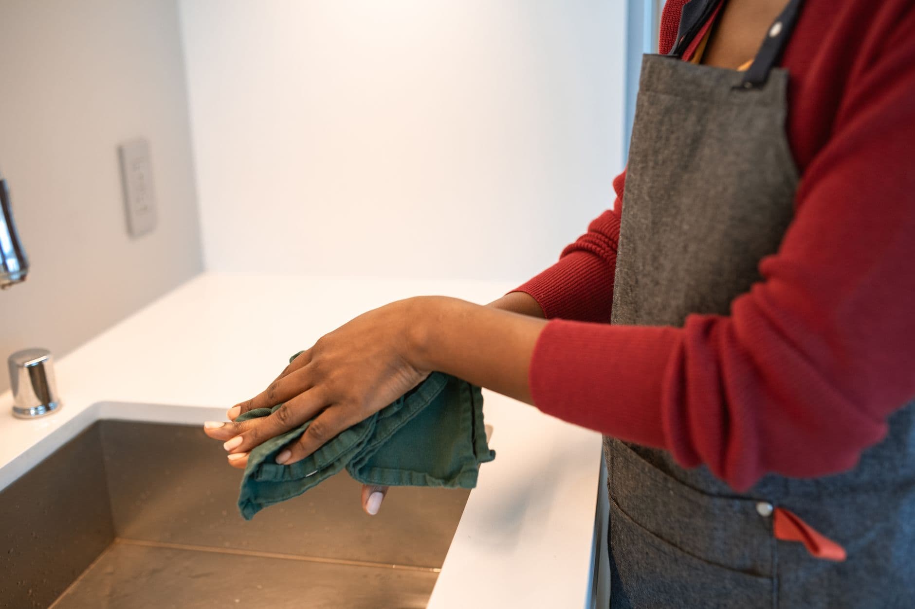 A cleaner wiping down a kitchen counter until it shines